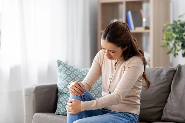 Asian woman suffering from ache in leg at home — Stock Photo, Image