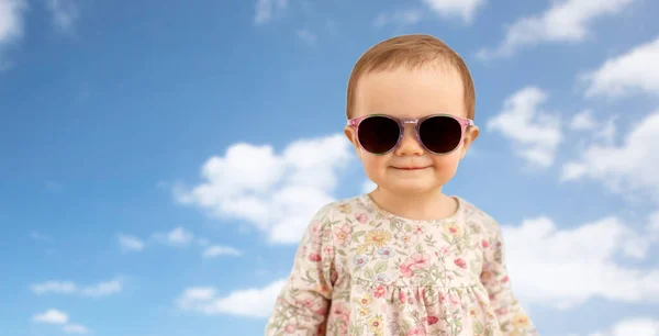 Niña feliz en gafas de sol sobre el cielo azul — Foto de Stock