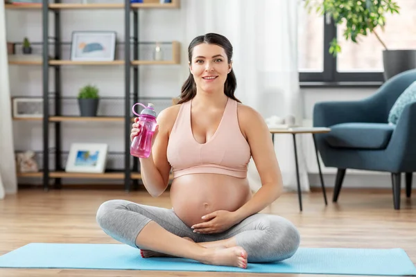 Mulher grávida bebendo água após ioga em casa — Fotografia de Stock