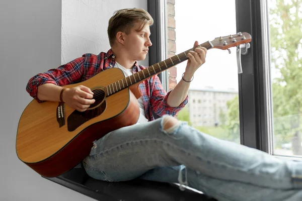 Joven tocando guitarra sentado en el alféizar de la ventana — Foto de Stock