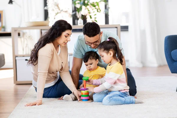 Família feliz brincando com brinquedo pirâmide em casa — Fotografia de Stock