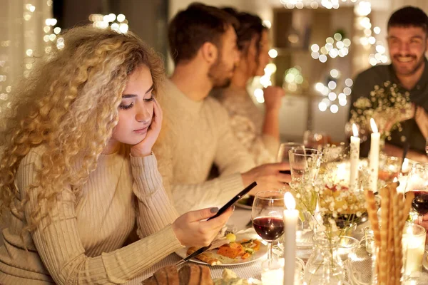 Mulher com smartphone no jantar com amigos — Fotografia de Stock