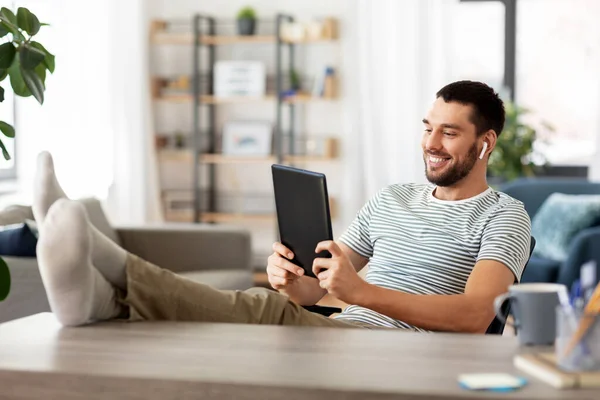 Felice uomo con tablet pc e auricolari a casa — Foto Stock