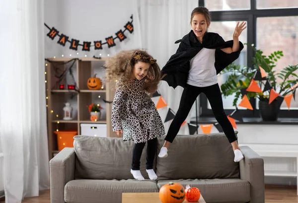 Девушки в костюмах на Хэллоуин прыгают на диване — стоковое фото