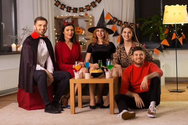 Amigos felices en disfraces de Halloween en la fiesta en casa —  Fotos de Stock