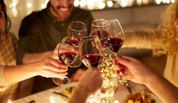 Glada vänner dricker rött vin på julfesten — Stockfoto