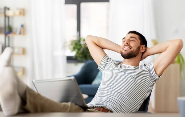 Щасливий чоловік з ноутбуком відпочиває в домашньому офісі — стокове фото