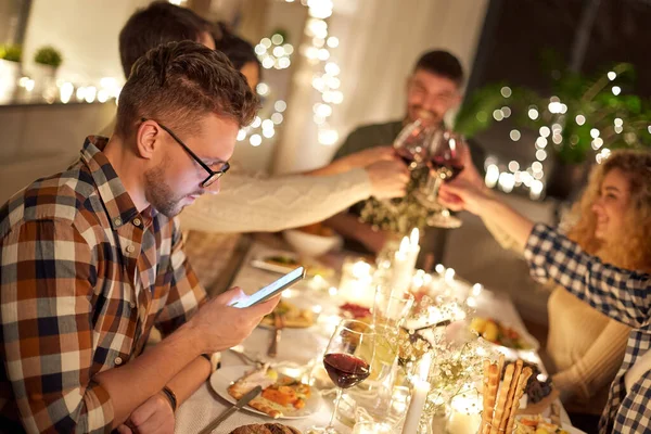 Мужчина со смартфоном на званом ужине с друзьями — стоковое фото