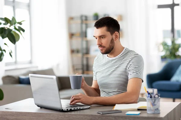 Man med bärbar dator dricka kaffe på hemmakontoret — Stockfoto