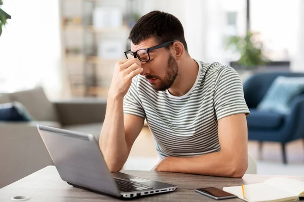 Homem cansado com laptop trabalhando no escritório em casa — Fotografia de Stock