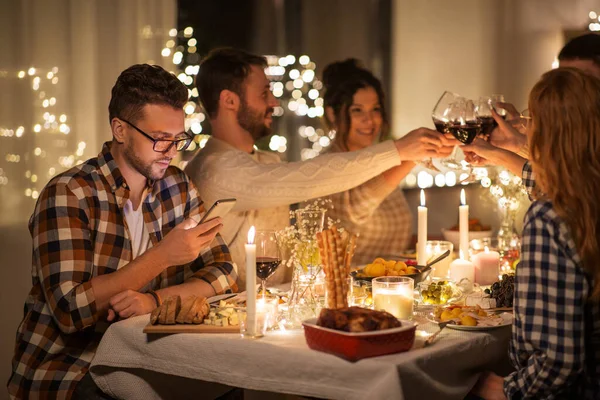Man with smartphone at dinner party with friends — Stock Photo, Image