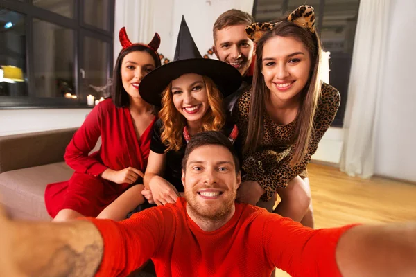 Amigos felices en disfraces de Halloween tomando selfie —  Fotos de Stock