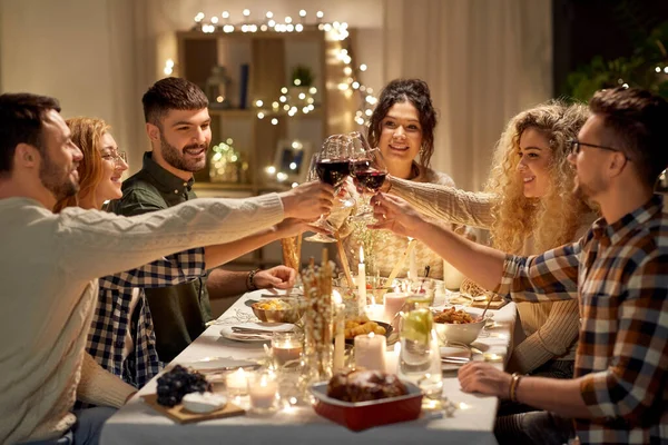 Glada vänner dricker rött vin på julfesten — Stockfoto