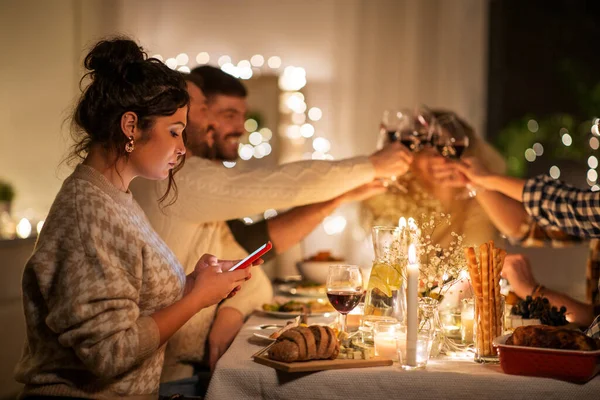 Frau mit Smartphone auf Dinnerparty mit Freunden — Stockfoto