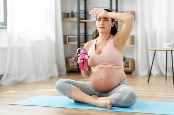 Schwangere trinkt Wasser nach Yoga zu Hause Stockbild