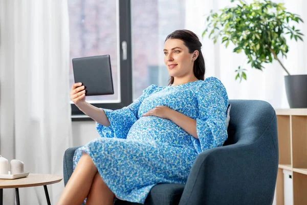 Heureuse femme enceinte avec tablette pc à la maison — Photo