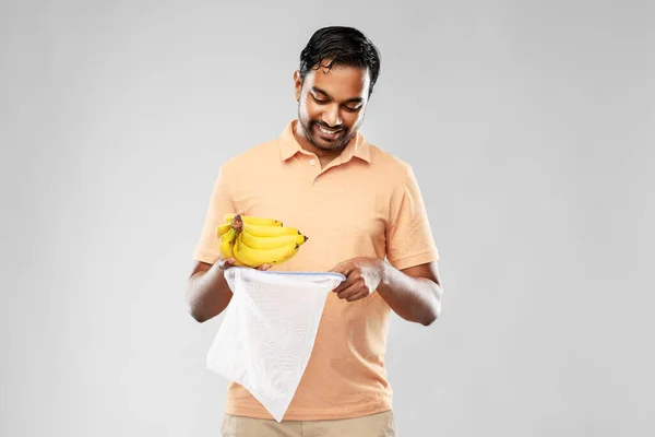 Pria bahagia menempatkan pisang ke dalam tas string dapat digunakan kembali — Stok Foto