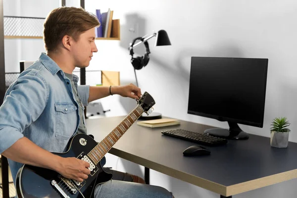 집에서 컴퓨터로 기타를 치고 있는 젊은이 — 스톡 사진