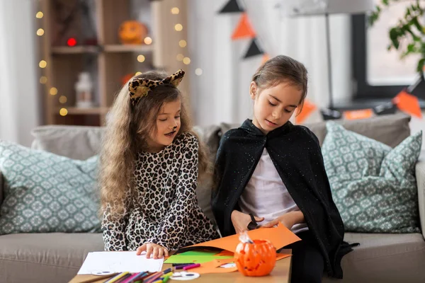 Meisjes in halloween kostuums doen ambachten thuis — Stockfoto