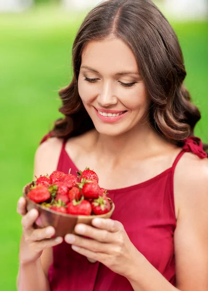 Mulher feliz comendo morango no parque de verão — Fotografia de Stock