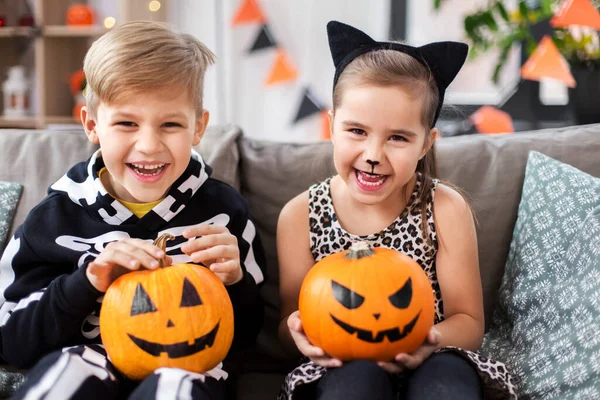 Crianças em trajes de Halloween com abóboras em casa — Fotografia de Stock