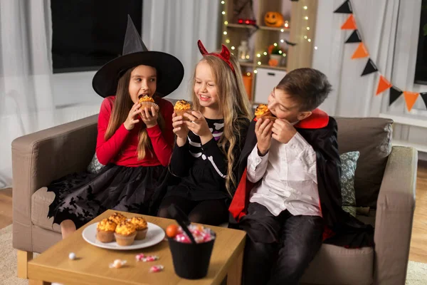 ハロウィンの衣装を着た子供たちが家でカップケーキを食べて — ストック写真