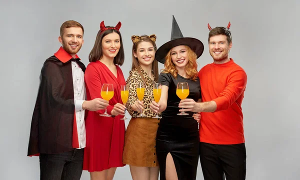 Glada vänner i halloween kostymer över grå — Stockfoto