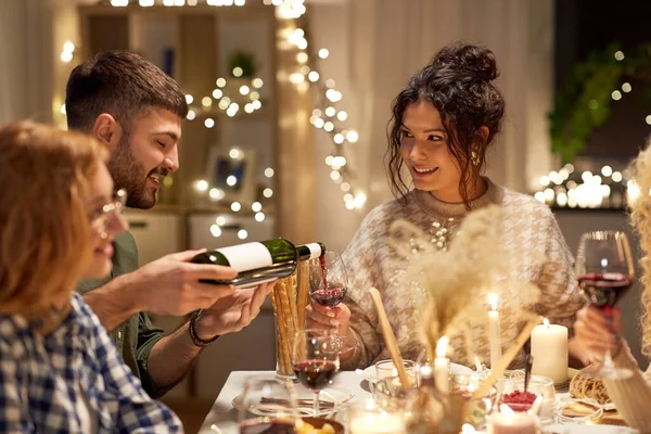Щасливі друзі з червоним вином на різдвяній вечірці — стокове фото