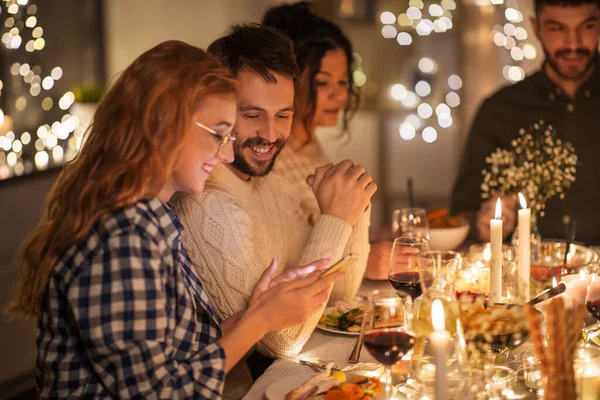 Amigos com celular tendo jantar em casa — Fotografia de Stock