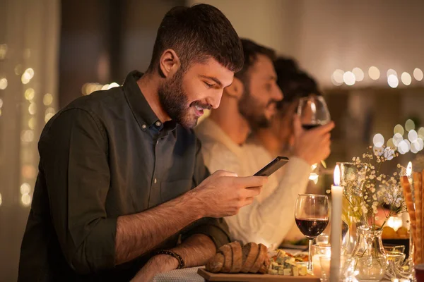 Homem com smartphone no jantar com amigos — Fotografia de Stock