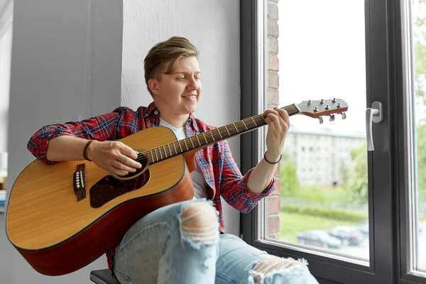 Young man playing guitar sitting on windowsill — Stock Photo, Image