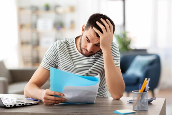 Man with papers and laptop working at home office — Stock Photo, Image