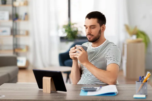 Man with tablet pc drinking coffee at home office — Stock Photo, Image