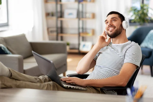 Homme heureux avec ordinateur portable et écouteurs à la maison — Photo
