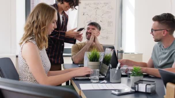 Женщина показывает смартфон коллегам в офисе — стоковое видео