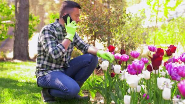 Hombre de mediana edad con teléfono inteligente en el jardín de flores — Vídeo de stock