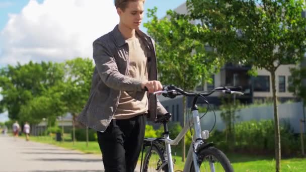 Junger Mann mit Fahrrad läuft Stadtstraße entlang — Stockvideo