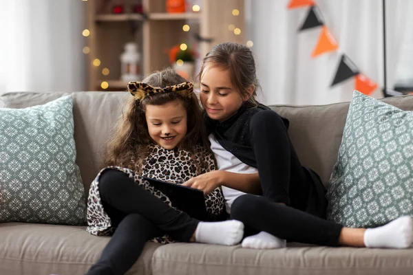 Meisjes in halloween kostuums met tablet pc thuis — Stockfoto