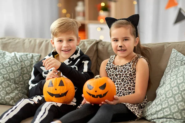 Ungar i halloween kostymer med pumpor hemma — Stockfoto
