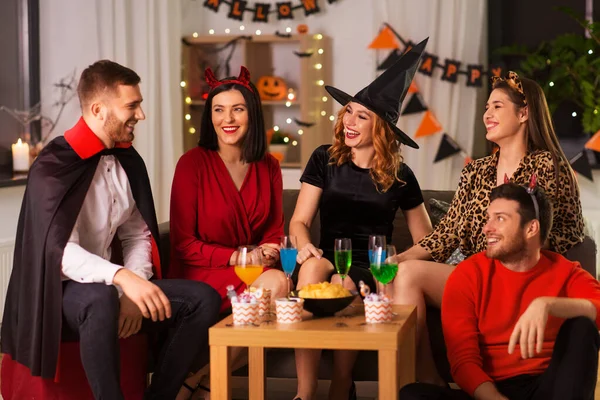 Счастливые друзья в костюмах Хэллоуина на домашней вечеринке — стоковое фото