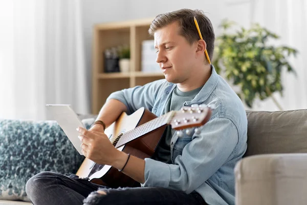 young man with guitar and music book at home