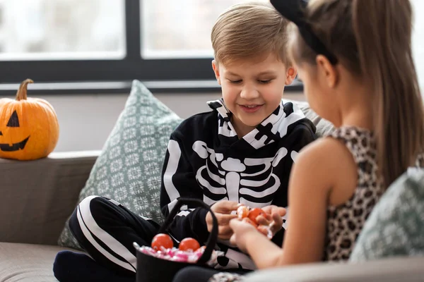 Kids in halloween costumes with candies at home — Stock Photo, Image