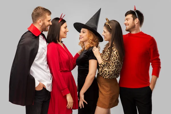 Glada vänner i halloween kostymer över grå — Stockfoto