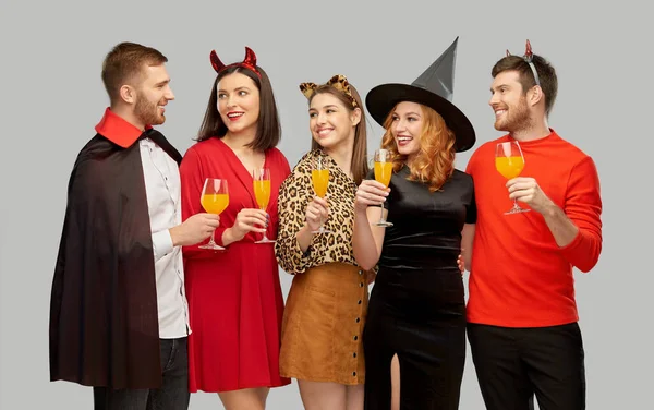 Gelukkig vrienden in halloween kostuums over grijs — Stockfoto