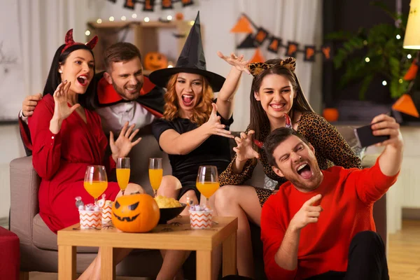 Glada vänner i halloween kostymer tar selfie — Stockfoto