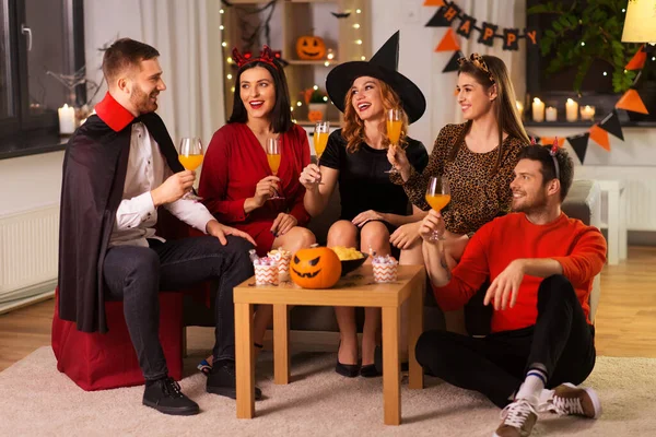 Amigos felices en disfraces de Halloween en la fiesta en casa —  Fotos de Stock