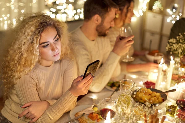 Mulher com smartphone no jantar com amigos — Fotografia de Stock