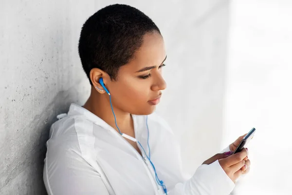 Afrikansk amerikansk kvinna med hörlurar och telefon — Stockfoto