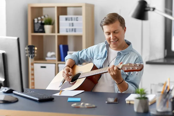 Jeune homme jouant de la guitare assis à table à la maison — Photo