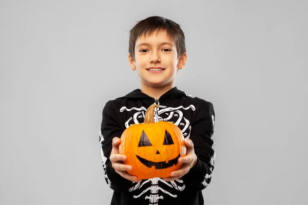 Jongen in halloween kostuum van skelet met pompoen — Stockfoto